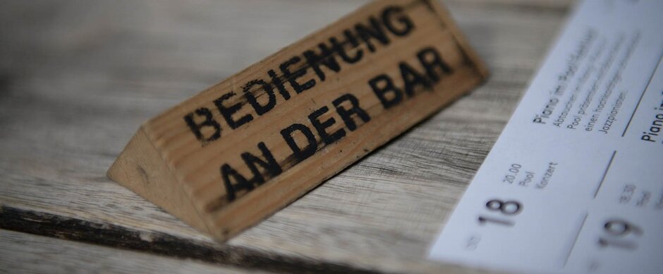 Hölzerner Tischaufsteller mit Aufschrift "Bedienung an der Bar"